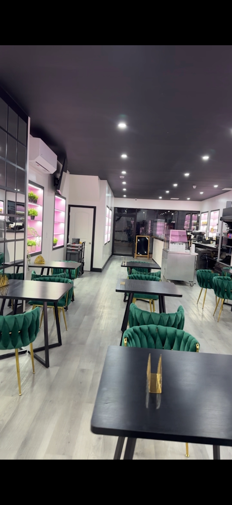 Café Mia interior at 1128 Broadway — emerald velvet seating, pink-lit shelves and cherry blossom installation. Best new cafe in Bushwick, Brooklyn